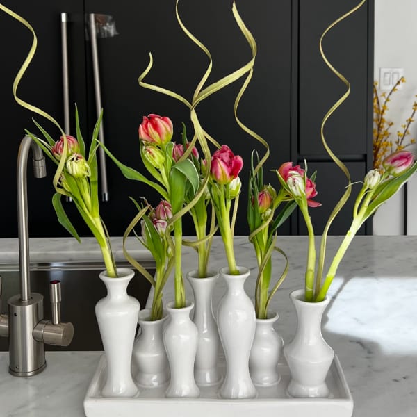 Pink tulips in white bud vases on a tray