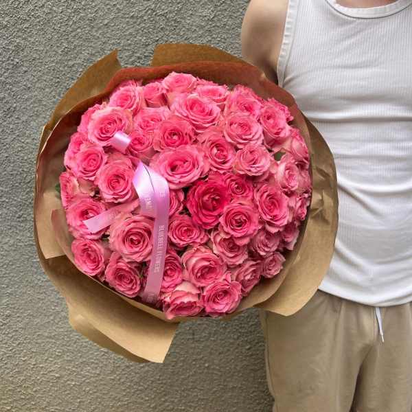 Large bouquet of pink roses wrapped in brown paper