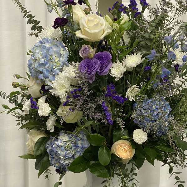 Mixed bouquet in a white vase with blue, purple, and white flowers