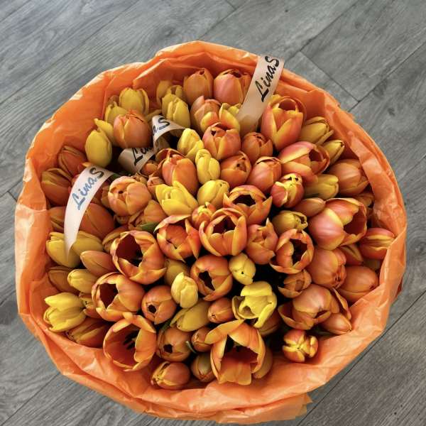 Bouquet of orange and yellow tulips wrapped in orange paper