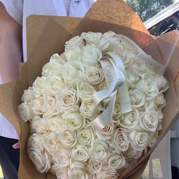Large bouquet of white roses wrapped in brown paper