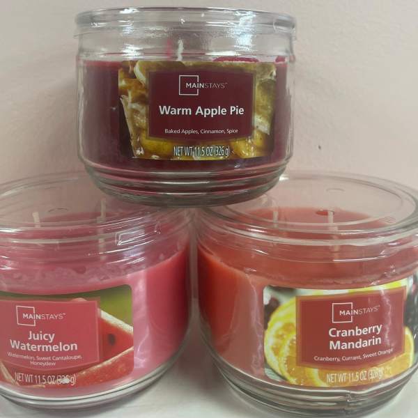 Set of three scented glass jar candles stacked in a small pyramid on a light background.