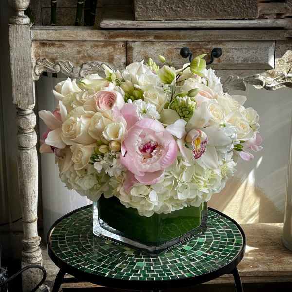 Bouquet of white and blush flowers in a square glass vase