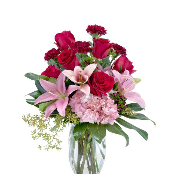 Pink lilies and red roses arranged in a clear glass vase