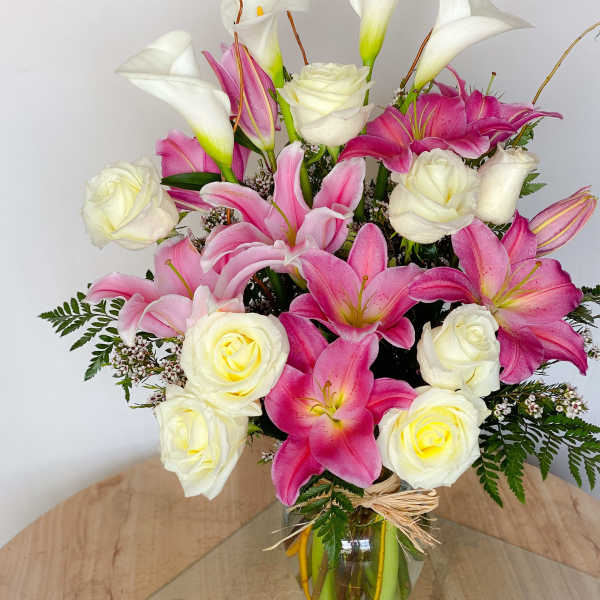 Pink lilies and white roses arranged in a glass vase