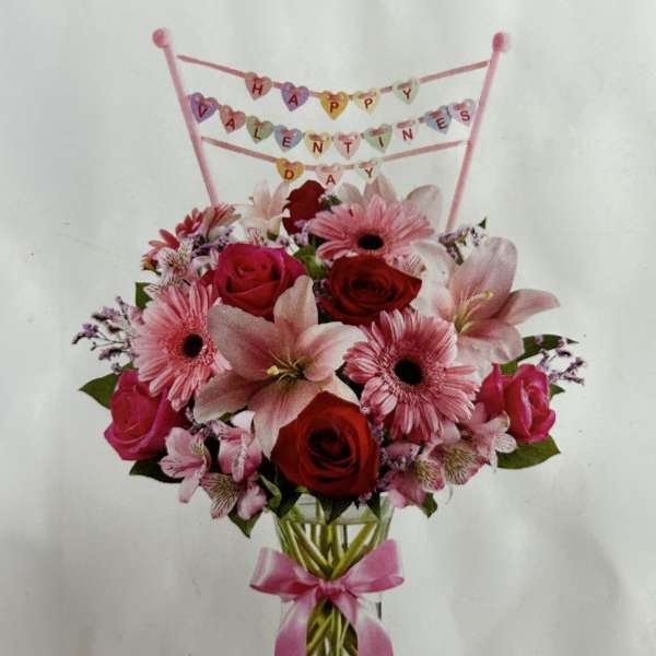 Pink and red flower bouquet in a glass vase with a Happy Valentine's Day topper