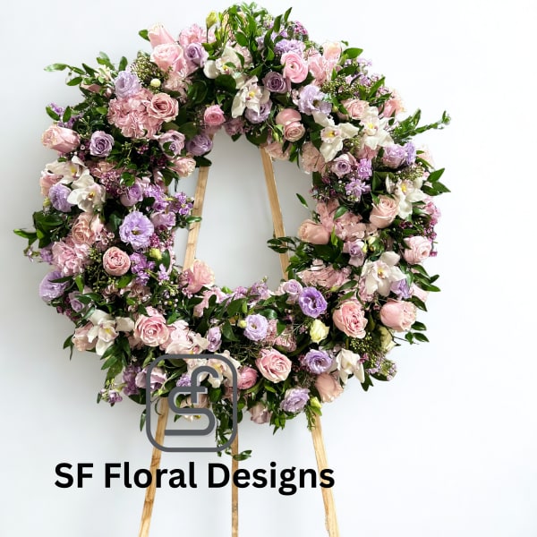 Standing wreath of pink and lavender roses and lisianthus on a wooden easel against a white background