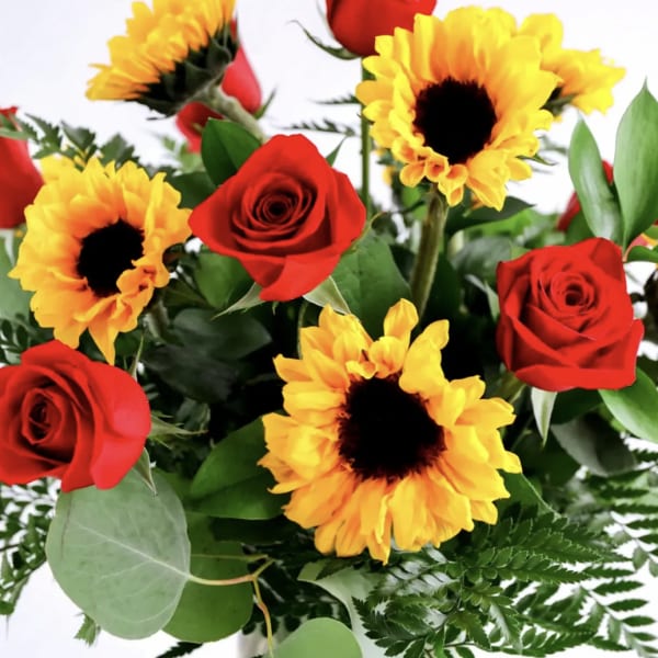 Bouquet of red roses and yellow sunflowers with greenery