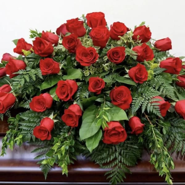 Large arrangement of red roses with greenery on a casket