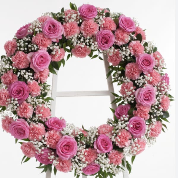 Pink rose and carnation wreath with baby's breath on a white stand