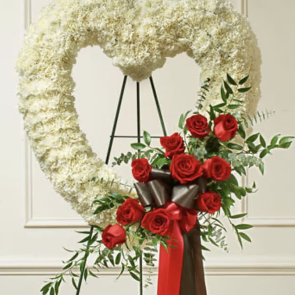 Heart-shaped white floral wreath with red roses and ribbon