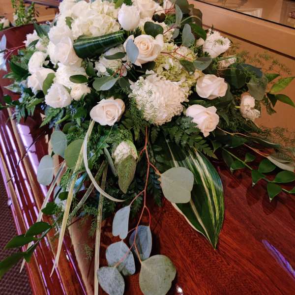 White floral casket spray with roses and hydrangea