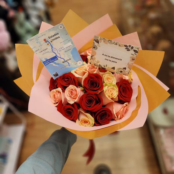 Handheld bouquet of red and peach roses wrapped in pink and gold paper
