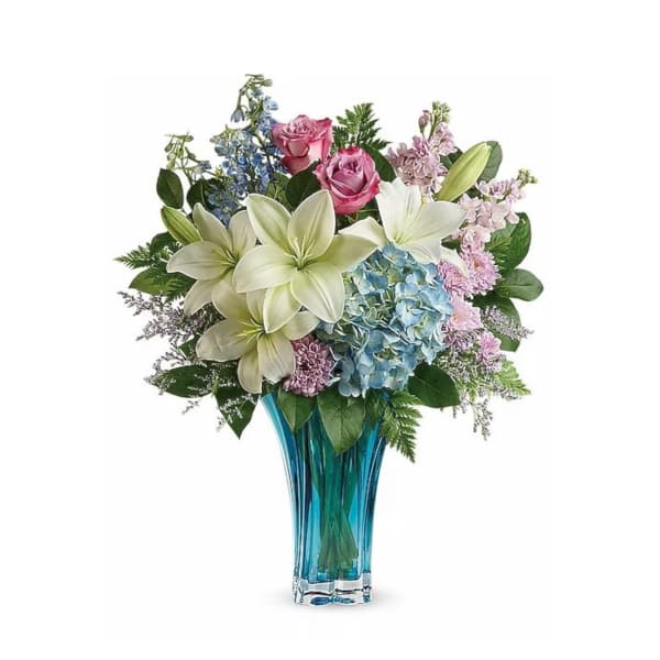 Bouquet of lilies, roses, and hydrangeas in a blue glass vase