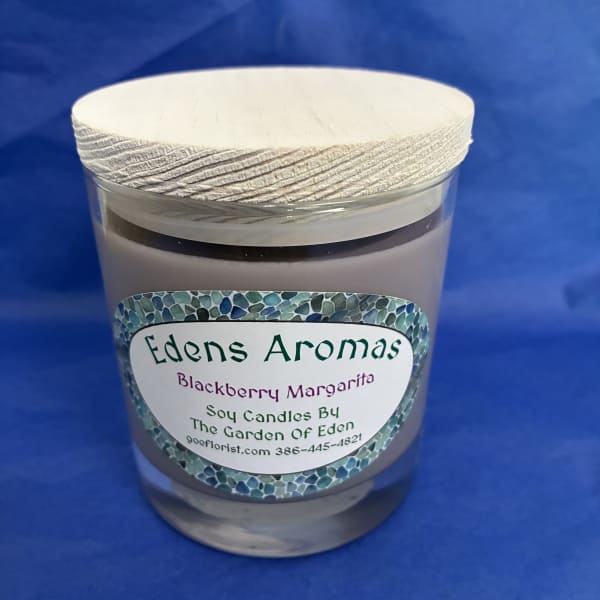 Glass jar soy candle with light wood lid and Blackberry Margarita label on a blue background