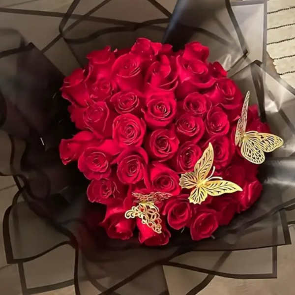 Bouquet of red roses wrapped in dark paper with butterfly decorations