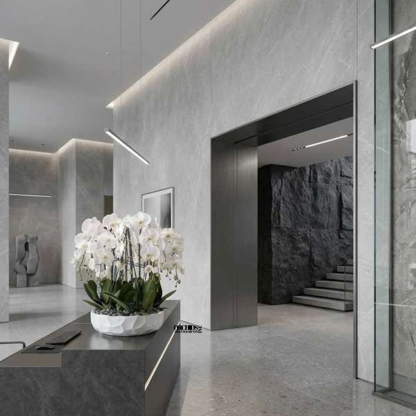 White phalaenopsis orchids in a low white bowl planter with stones on a modern gray reception desk