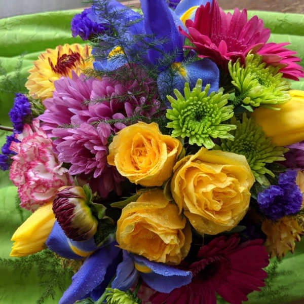 Bright mixed bouquet with roses, daisies, and tulips on green fabric