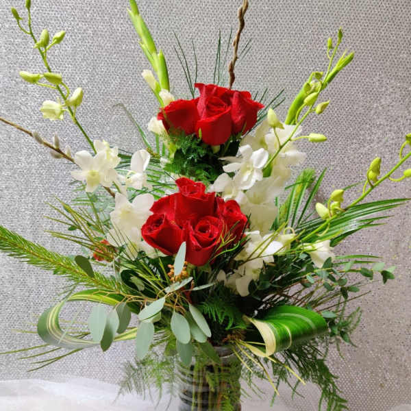 Red roses and white orchids in a clear glass vase