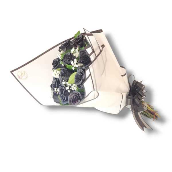 Bouquet of black roses with small white filler flowers wrapped in white paper with dark ribbon