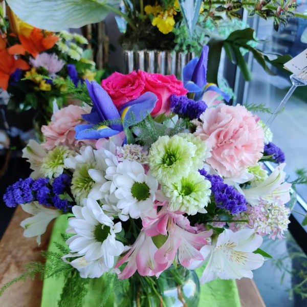 Mixed bouquet of pink, white, purple, and blue flowers in a glass vase