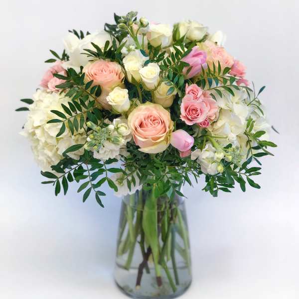 Pink and white roses arranged in a clear glass vase