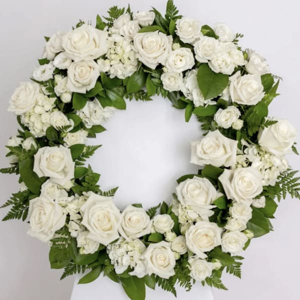 White rose wreath with green foliage on a white background