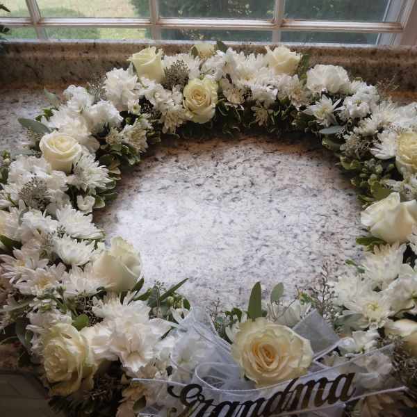White floral wreath with roses and daisies on a countertop
