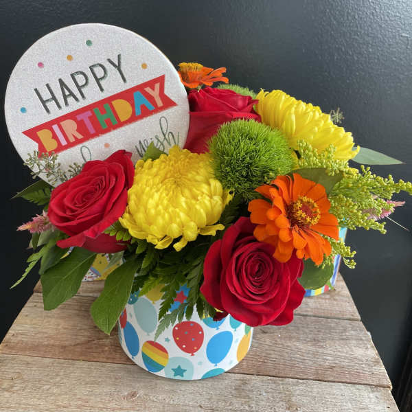 Birthday flower arrangement with roses, mums, and a greeting card topper