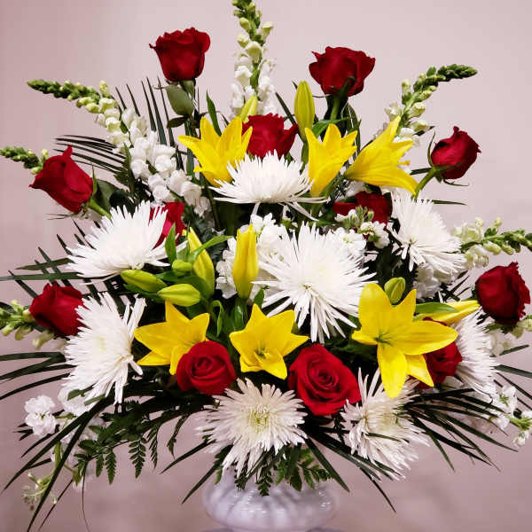 Large bouquet of red roses, yellow lilies, and white spider mums in a white vase