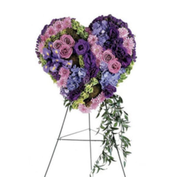 Heart-shaped floral standing spray in purple, pink, and blue on a metal easel