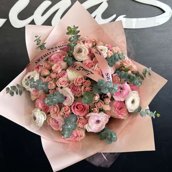 Pink and white bouquet of roses and ranunculus wrapped in blush paper