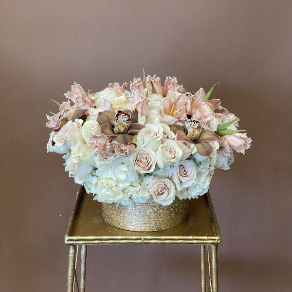 Blush and white floral arrangement in a gold round box