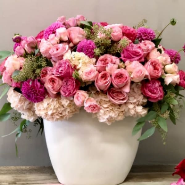 Pink and cream rose arrangement in a white vase