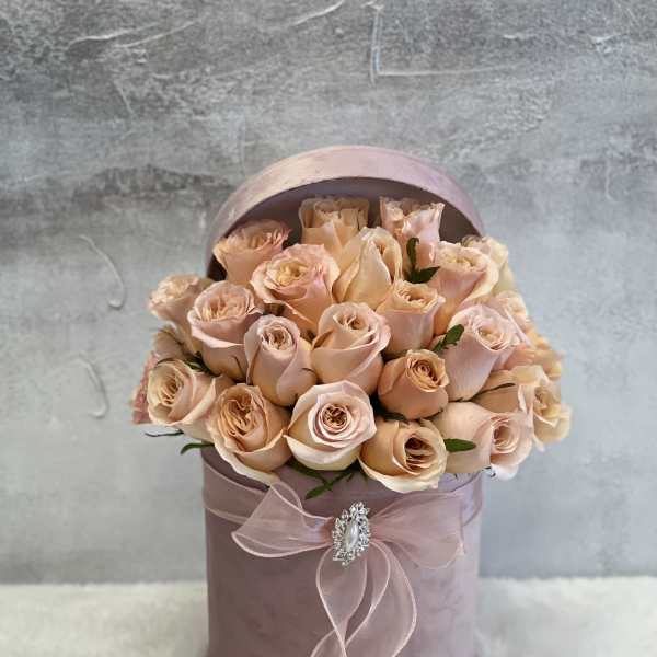Round blush hatbox filled with peach roses and tied with a sheer pink bow
