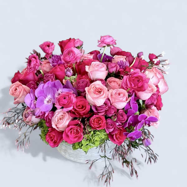 Pink and purple rose bouquet in a low white vase
