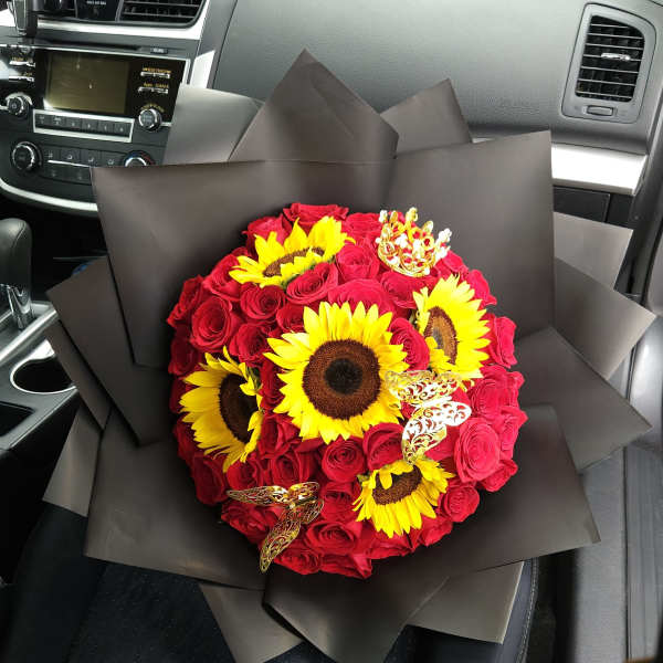 Bouquet of red roses and yellow sunflowers wrapped in black paper