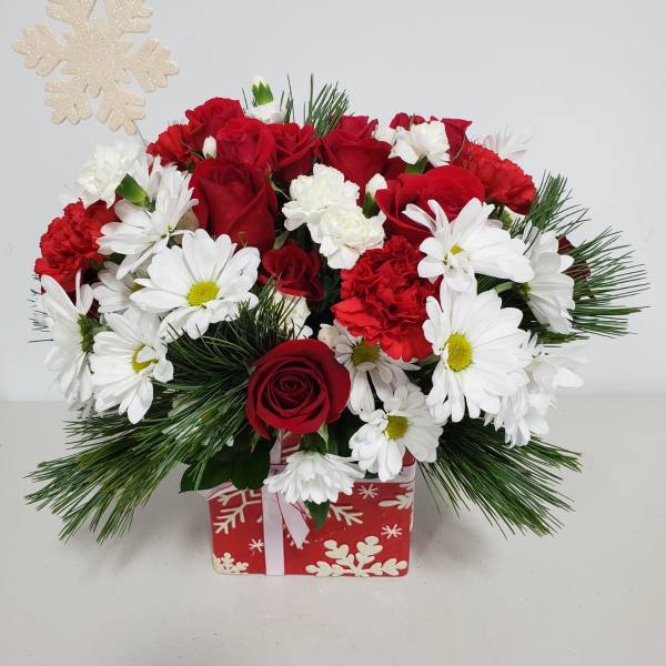 Red roses and white daisies in a holiday gift box with a snowflake pick