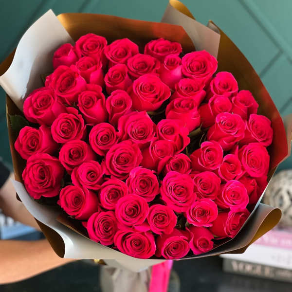 Bouquet of bright pink roses wrapped in brown and white paper