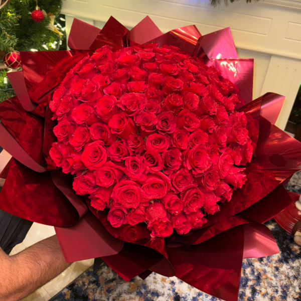 Large bouquet of red roses wrapped in glossy red paper