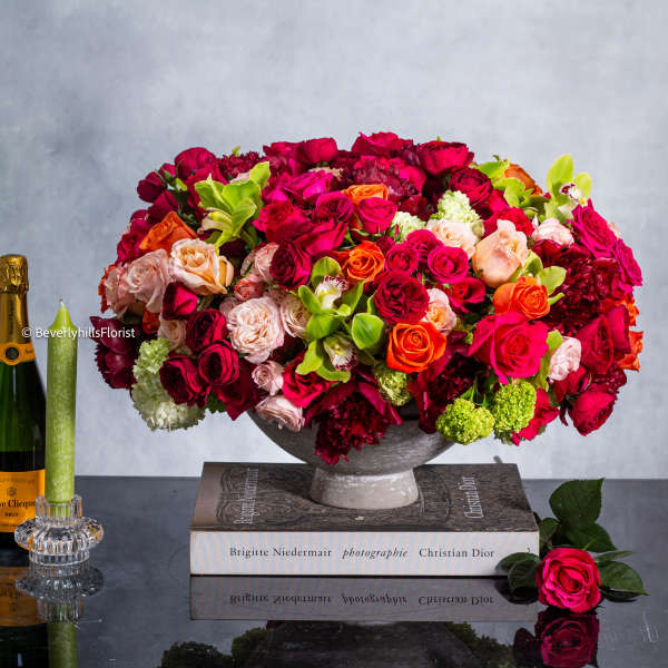 Large arrangement of red, pink, and orange roses in a pedestal bowl