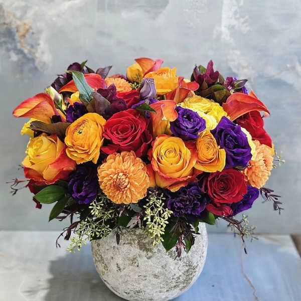 Mixed bouquet of roses, calla lilies, and dahlias in a stone vase