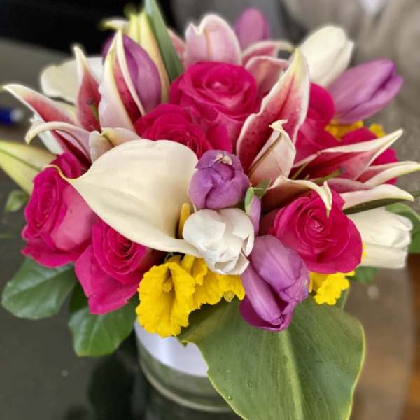 Bouquet of pink roses, white calla lilies, and purple tulips in a vase