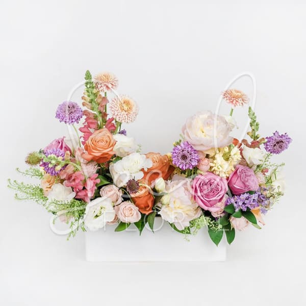 Two pastel floral arrangements in a white basket with roses and dahlias