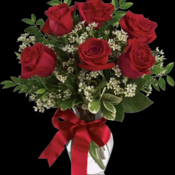 Red roses in a clear glass vase with a red ribbon