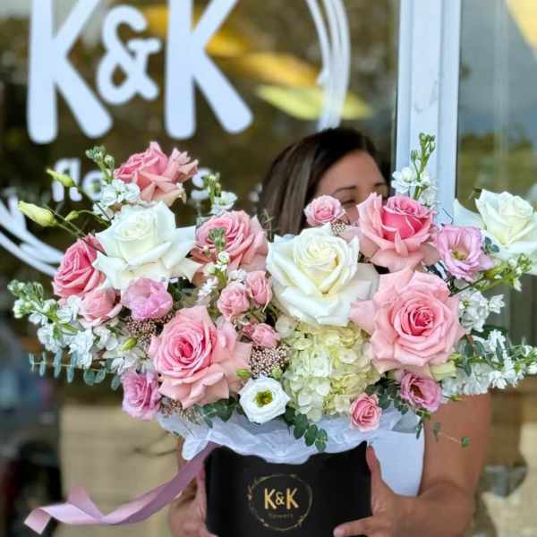 Large pink and white rose arrangement in a black hat box