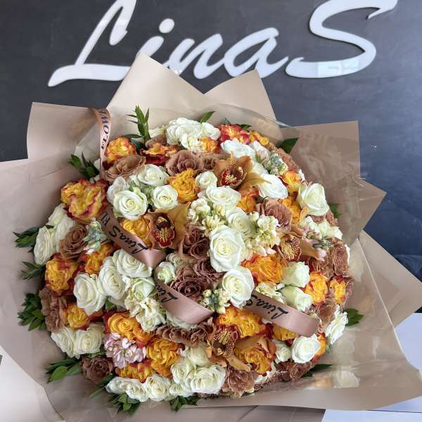 Large bouquet of white, tan, and yellow-orange roses wrapped in beige paper
