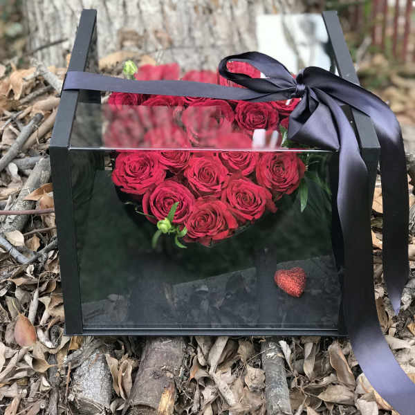 Heart-shaped box of red roses tied with a black ribbon