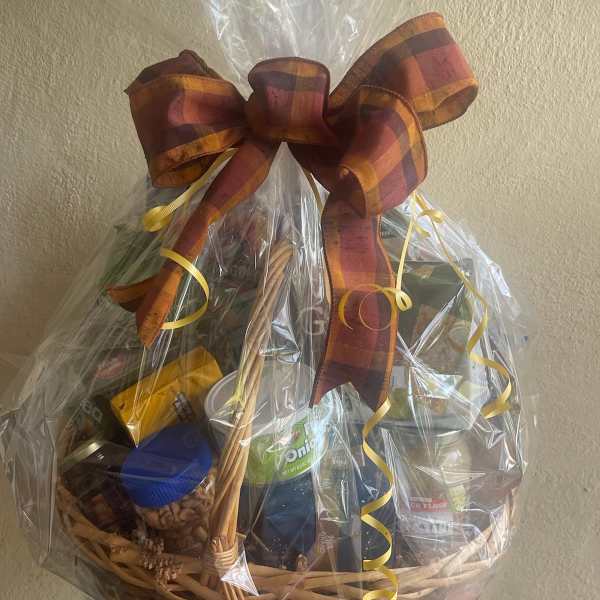 Gift basket of assorted packaged foods wrapped in cellophane with a plaid bow
