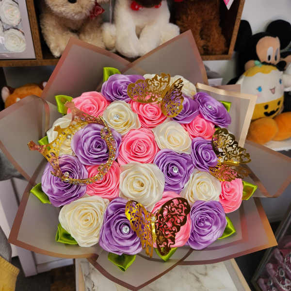 Bouquet of satin roses in pink, purple, and white with butterfly picks